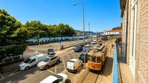 Rua com carros estacionados, um eléctrico e um edifício com fachada marcante.