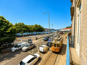 Eine Straße mit parkenden Autos, einer Straßenbahn und einem Gebäude mit einer markanten Fassade.