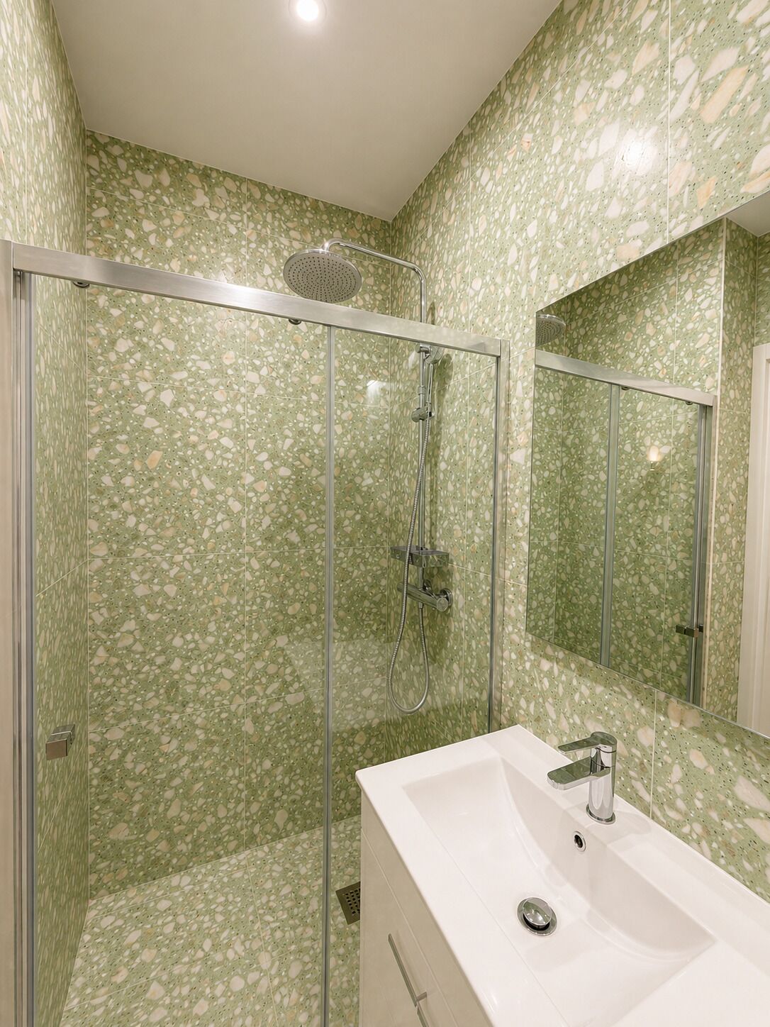 Une salle de bain avec une douche à parois de verre, un lavabo blanc et un miroir.