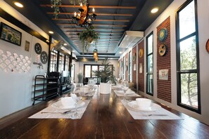 A long dining table with white placemats and empty wine glasses, set against a brick wall with decorative plates and a large window. - PAPA Beach Pool Villas Pattaya (Bang Lamung District)