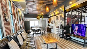 A modern lounge area with a leather sofa, wooden flooring, and a television. - PAPA Beach Pool Villas Pattaya (Bang Lamung District)