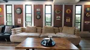 Una sala de estar con un sofá modular, una mesa de centro y una pared de ladrillo decorada con objetos antiguos.