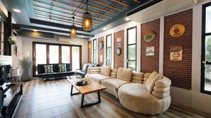 A modern interior with a sectional sofa, a wooden coffee table, and a brick wall with vintage beer and coffee signs. - PAPA Beach Pool Villas Pattaya (Bang Lamung District)