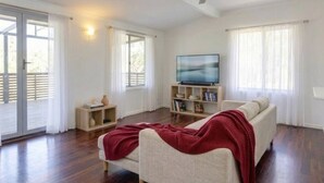 A living room with a sofa, a television, a bookshelf, and a ceiling fan.