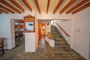 Eine Treppe mit Steinstufen führt zu einer zweiten Etage, ein spiegel mit Holzrahmen und ein Küchenbereich im Hintergrund.