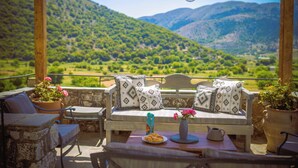 A wooden pergola with a white sofa, a table with a plate of cookies, a vase with flowers, and a pitcher. - Traditional Villas Askyfou (Askyfou)
