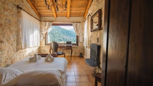 A bedroom with a bed, a desk, a chair, a mirror, and a view of mountains. - Traditional Villas Askyfou (Askyfou)