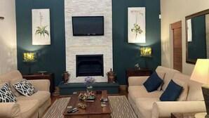 A living room with two sofas, a coffee table, a fireplace, and wall-mounted TV. - Dream Holiday Home in the Heart of Franschhoek (Franschhoek)