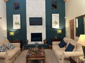 A living room with two sofas, a coffee table, a fireplace, and wall-mounted TV. - Dream Holiday Home in the Heart of Franschhoek (Franschhoek)