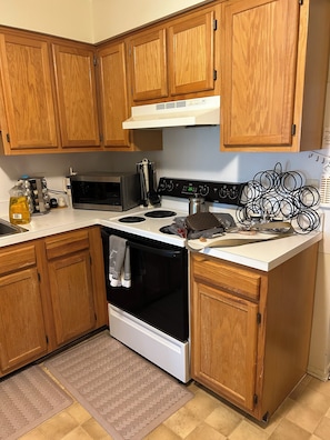 Eine Küche mit Holzausstattung, einer Mikrowelle, einem Herd und verschiedenen Küchenutensilien.