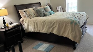 A bedroom with a bed, nightstand, lamp, chair, and a window. - Cozy 1-bedroom apartment with AC in serene Farmington Hills (Farmington Hills)