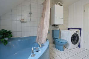 Ein Badezimmer mit einer blauen Badewanne, einer Toilette und einer Waschmaschine.