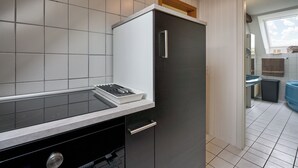 Una cocina moderna con estufa integrada, refrigerador negro y encimera blanca.