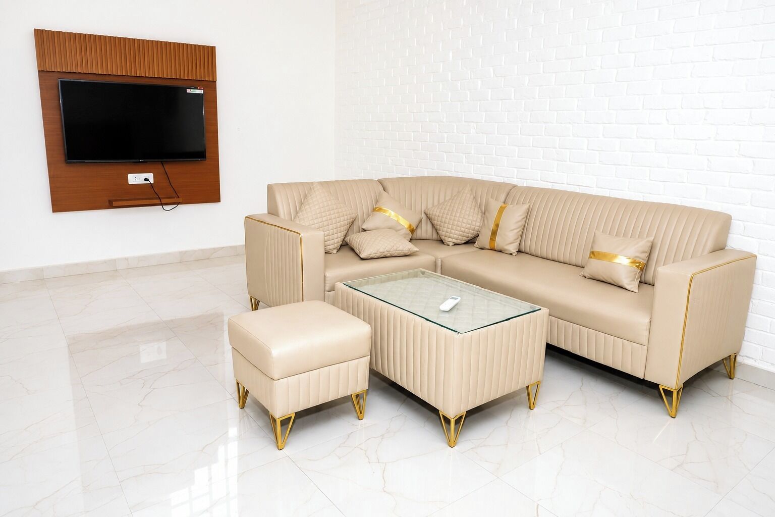 Uma sala de estar moderna com um sofá bege, um banquinho coordenado e uma mesa de centro de vidro.