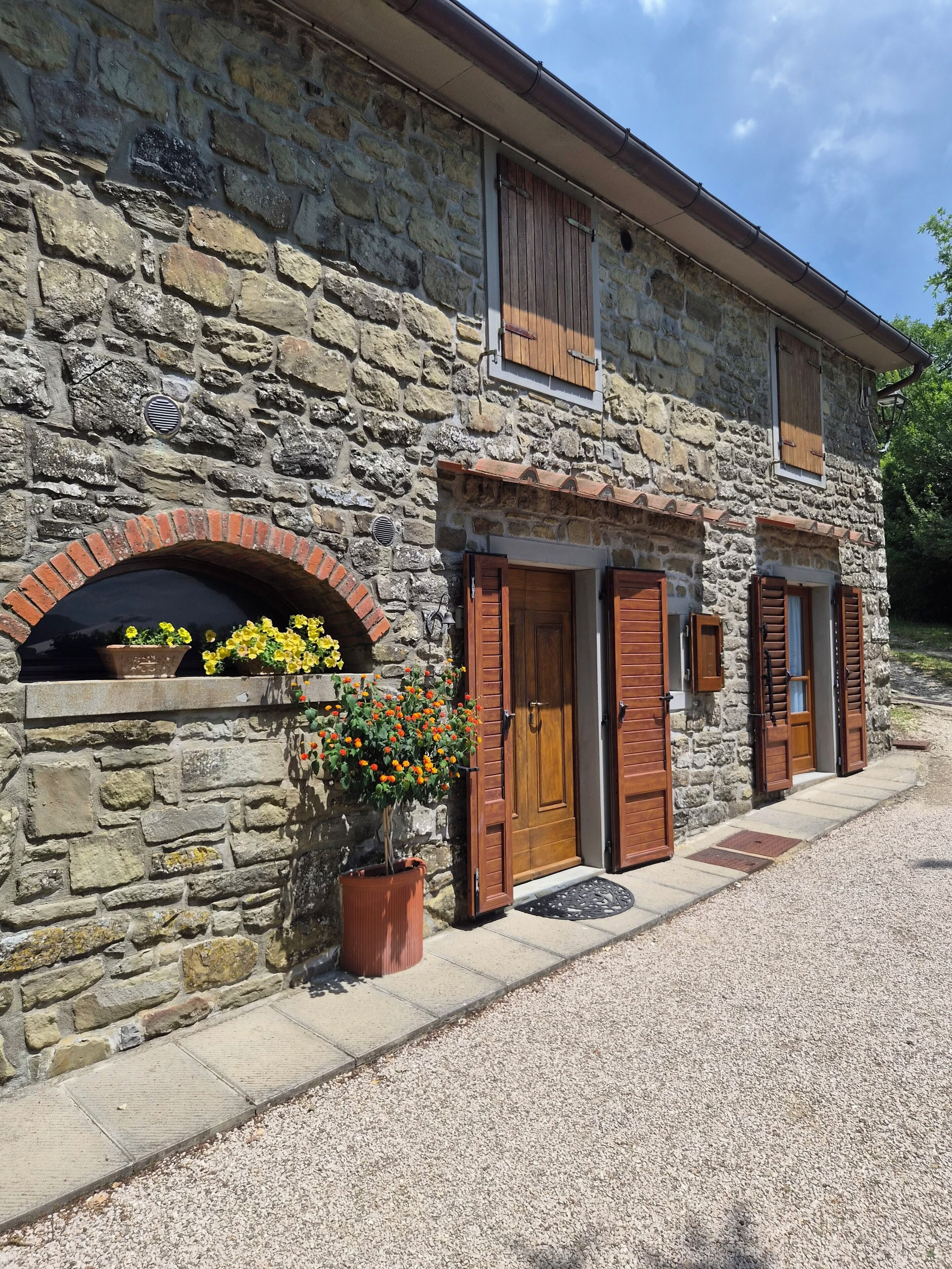 Un bâtiment en pierre avec une arche en briques, des portes en bois et une petite fenêtre.