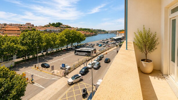 Un balcon donnant sur une rivière, des voitures garées et un autobus.