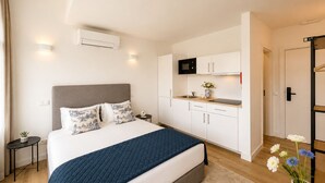 Une chambre d’hôtel moderne équipée d’un lit, d’une kitchenette et d’une porte donnant sur une autre pièce.