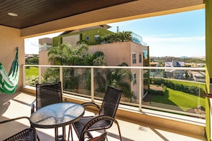 Un balcón con mobiliario de mimbre y vistas a un edificio con vegetación.
