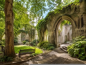 An ancient stone structure with arches, surrounded by lush greenery and a well-maintained lawn. - City Monument London Bridge Riverside Serviced Apt (London)