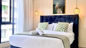 A modern bedroom with a large bed, a dark headboard, and two pendant lights. - Shamm Goldpark homes 1bd (Nairobi)