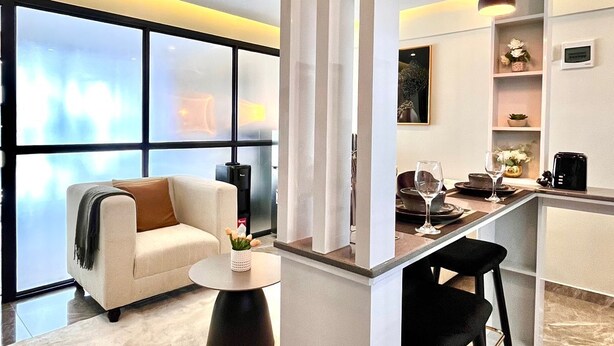 A modern living area with a sofa, coffee table, and bar area with stools. - Shamm Goldpark homes 1bd (Nairobi)