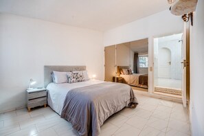 A bedroom with a bed, bedside table, lamp, and a sliding glass door leading to a bathroom. - Vivenda Nos Dois - 3 Bed Villa With Heated Pool (Carvoeiro)