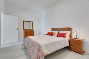 Un dormitorio con cama, mesitas de noche, armario y espejo.