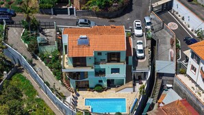 A multi-story house with a swimming pool, a solar panel, and a garage.