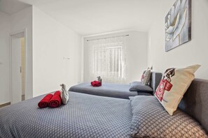 A hotel room with two beds, a window with sheer curtains, and a wall-mounted artwork. - Holiday House Nives with pool and playground (Orihi)