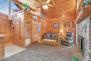 Ein gemütliches Blockhaus-Interieur mit Kamin, Ledersitzmöbeln und Deckenventilator.