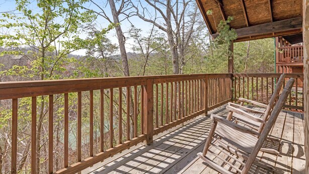 Um deck de madeira com guarda-corpo, com vista para uma área arborizada.