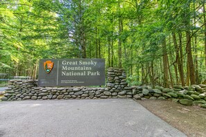Schild für den Great Smoky Mountains Nationalpark, mit einer Steinmauer und bewaldeter Landschaft im Hintergrund.