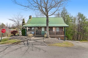 Ein Chalet mit einem grünen Metalldach, einer Veranda und einem Verkehrsschild in der Nähe.