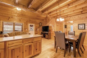 A wooden cabin interior with a kitchen, dining area, and a staircase leading to upper levels. - 1 Mile to Pigeon Forge・Charming Log Cabin・Hot Tub (Pigeon Forge)