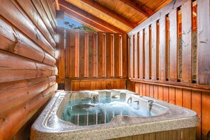 A hot tub in a wooden cabin with a sloped ceiling and wooden walls. - 1 Mile to Pigeon Forge・Charming Log Cabin・Hot Tub (Pigeon Forge)