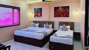 Habitación de hotel con dos camas, ventilador de techo, aire acondicionado instalado en la pared y obras de arte.