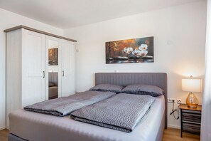 A bedroom with a bed, a nightstand, a lamp, a wardrobe, and a painting on the wall. - Dog-Friendly Apartment with Mountain Views (Bräunlingen)