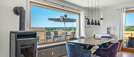 Un comedor moderno con una mesa grande, sillas y vistas a través de un ventanal.