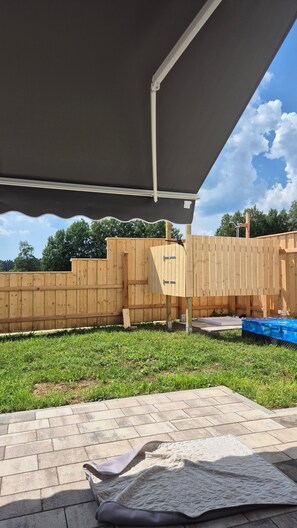 A backyard with a wooden fence, a covered patio area, and a blue pool. - Dog-Friendly Apartment with Mountain Views (Bräunlingen)