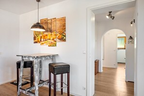 A modern kitchen with a wooden table, two stools, and a hanging pendant light. - Dog-Friendly Apartment with Mountain Views (Bräunlingen)