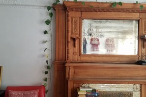 Ein Holzschrank mit Glastür, ein roter Stuhl und eine Bücherstapel auf einem Fliesenboden.