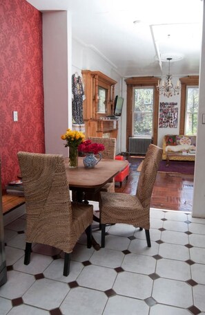 Ein Essbereich mit Holztisch, Korbstühlen, einem Blumenstrauß und einer Wand mit Muster.