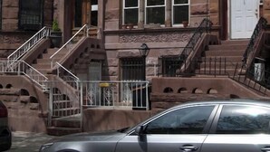 A row of three-story townhouses with a central entrance, a small porch, and a fire escape.