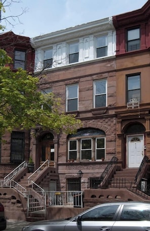 A row of three-story townhouses with a central entrance, a small porch, and a fire escape. - Maison de sirènes 2, Bohemian, ecclectic apartment (Brooklyn)