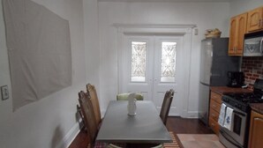 A dining area with a table, chairs, and a kitchen with appliances.
