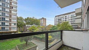 Ein Balkon mit Blick auf umliegende Gebäude und einen Garten.