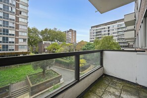 Un balcón con vistas a edificios circundantes y un jardín.