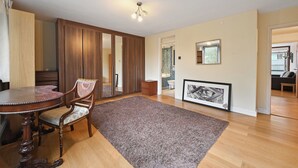 Ein Zimmer mit einem Holztisch, einem Stuhl, einem großen Spiegel und einem gerahmten Bild an der Wand.