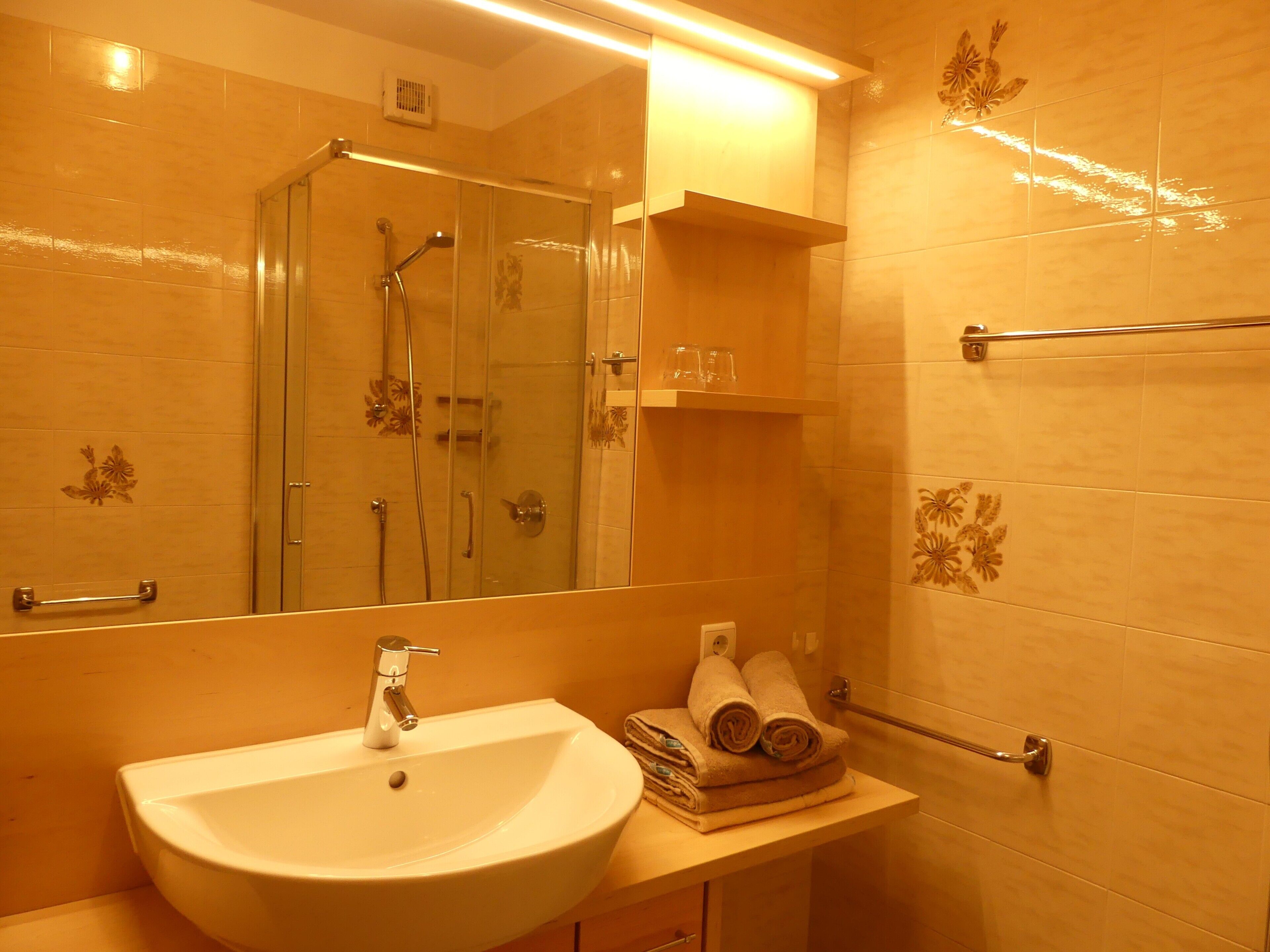 Un bagno con lavandino, specchio, doccia e portasciugamani.