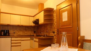 Eine Küche mit Holzausstattung, einer gefliesten Spritzschutzwand, einem Spülbecken und einem Tisch mit Spitzenunterlage.